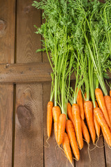 Fresh organic carrots with green leaves on wooden background. Vegetables. Healthy food.