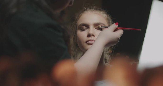 professional makeup artist making bright makeup for young attractive model 4k