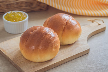 Round bun, bread rolls on wooden plate and pineapple jam