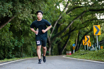 Active healthy runner jogging outdoor. Dinking water.