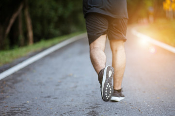 Starting day from morning jog. Full length rear view of young man in sports clothing jogging in park.Man in jogging shoes ready for a run outside at sunset