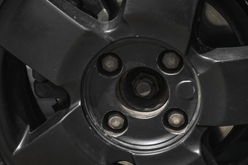 black wheel of a car with four bolts and brakes behind it