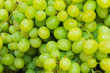 Green fresh grapes bunch lies in a wicker basket in the counter of a small market. 