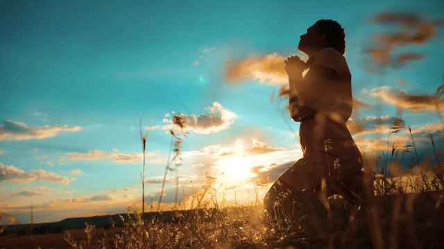girl praying. girl folded her lifestyle hands in prayer silhouette at sunset. slow motion video. Girl folded her hands in prayer pray to God. asks forgiveness for sins of repentance. believing girl