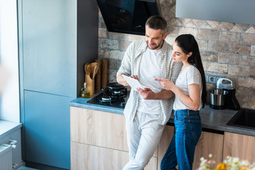 married couple using digital tablet together in kitchen, smart home concept - Powered by Adobe