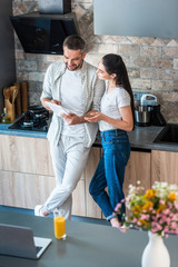 married couple using digital tablet together in kitchen, smart home concept