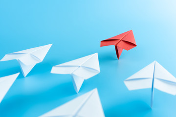 Leadership concept with red paper plane leading among white on blue background