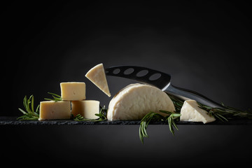 Sheep cheese with rosemary on a black background.