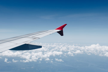 Fototapeta premium Wing of airplane flying on the white cloud, view at airplane window
