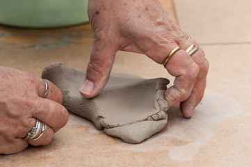 closeup of hands of old woman making clay pottery bowl in outdoor