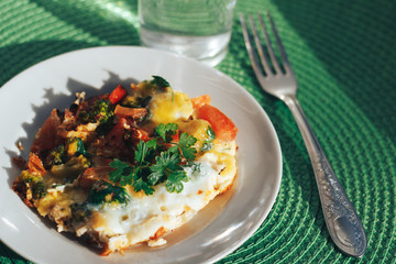 Scrambled eggs with tomatoes and greens on green background