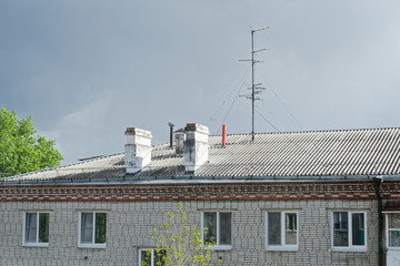 Chimneys and television areal on the roof of apartment house against cloudy sky. Komsomolsk-on-Amure, Russia