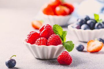 White ceramic bowl with fresh healthy berries. Raspberry, strawberry and blueberries. Copy space. Retro style toned.