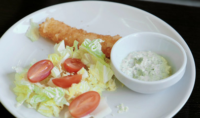 Close-up plate with vegetables and sauce, cheese stick on a plate.