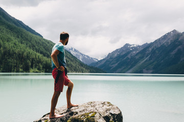 A man on a stone with a view of the mountains Kucherlinskoe lake, Altai, Russian Federation