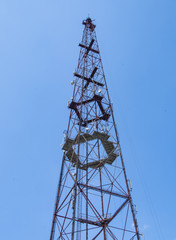 Telecommunication tower include of radio microwave and television antenna system with cloud blue sky and sun ray. Antenna tower, low angle view.