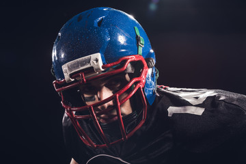 close-up portrait of serious american football player in helmet looking at camera isolated on black