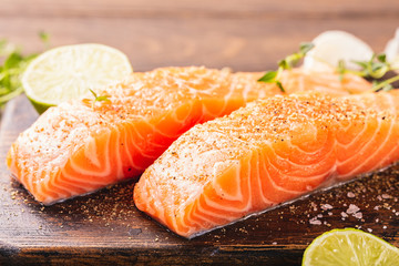 Fresh raw salmon fillet with aromatic herbs, spices on old wooden background. Toned.