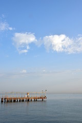 Fototapeta na wymiar Bootssteg am Meer vor blauen Himmel mit Wolken