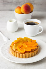 Cheesecake with apricots and jelly topping on a white plate and light background. 