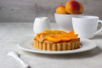 Cheesecake with apricots and jelly topping on a white plate and light background. 