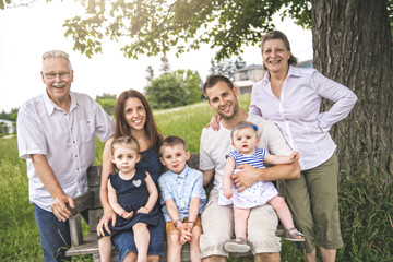 Family with grandparent spending time with little child during the sunset.