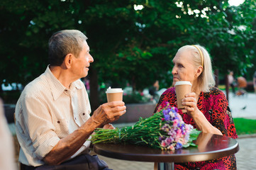 Elderly family couple talking and drinking tea ih the cafe on the street.