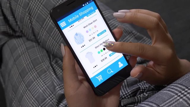 Young woman holding a smartphone and shopping for men cloths