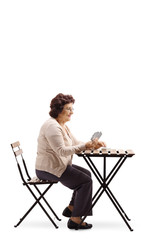 Senior lady sitting on a table and playing cards