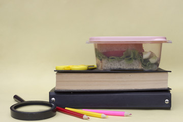 Plastic container, lunchbox with school lunch on a yellow background