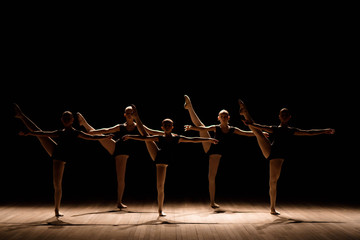 A choreographed dance of a group of graceful pretty young ballerinas practicing on stage in a classical ballet school