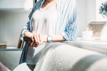 cropped shot of senior woman leaning on sofa at home