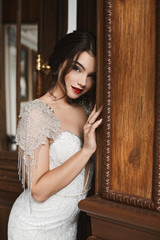 Beautiful, sexy and sensual brunette model girl with bright make-up, in stylish lace dress smiling and posing in luxury vintage interior