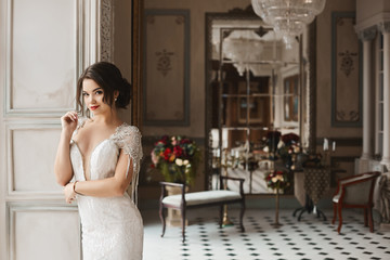 Beautiful, sexy and sensual brunette model girl with bright make-up and fashionable hairstyle, in stylish lace dress smiling and posing in luxury vintage interior