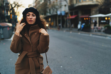 Half length portrait of a beautiful caucasian female wearing light brown coat touching her long...