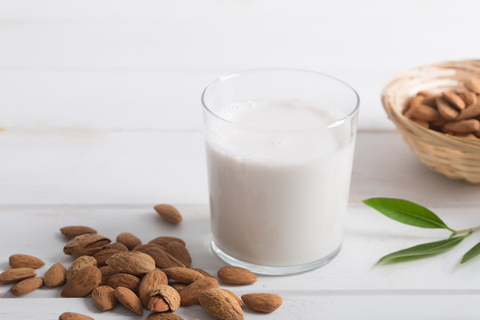 Almond milk in a glass on a white wooden table