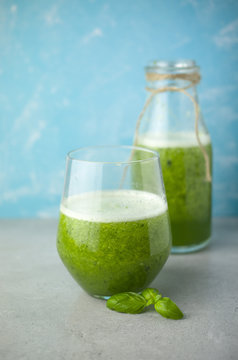 Blended green smoothie with ingredients on wooden table