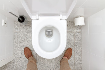 Mann steht vor einer Toilettenschüssel 