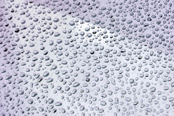 Raindrops, violet color on the window glass, selective focus. Natural background