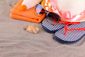 Fototapeta na wymiar Beach accessories. Hat, flip-flops, a towel and a shell in the sand of the sea