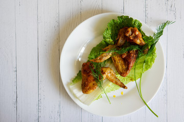 Fried chicken wings lie on a sheet of Peking cabbage in a white plate