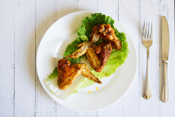 Fried chicken wings in a white plate lie on a light surface