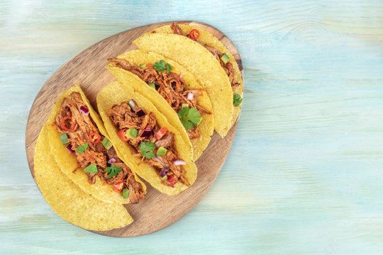 Overhead photo of Mexican tacos with pulled pork, avocado, chili peppers, cilantro, with place for text