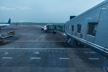 airplane at parking apron view from window of waiting hall of air terminal at dawn on a cloudy day