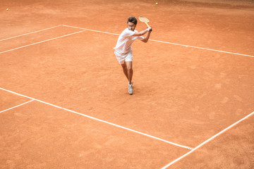 Obraz premium old-fashioned tennis player training with wooden racket on brown court