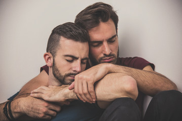 Gay couple going through rough times, comforting each other, experiencing quiet sadness