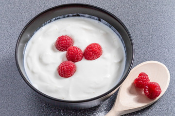 Close up view of a bowl full of fresh curd with raspberries