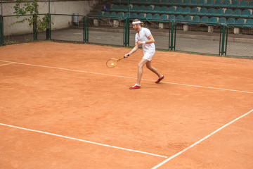retro styled man in white sportswear playing tennis with racket and ball on court