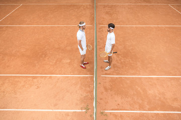 overhead view of tennis players in white sportswear with wooden rackets on court