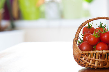 basket full of tomatoes in front of a green yellow blurry background on a wooden table